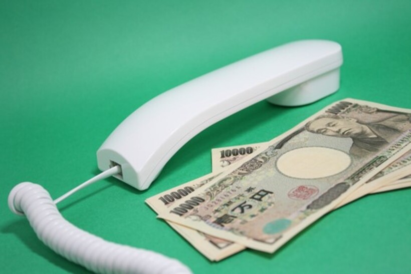 固定電話の受話器と1万円札数枚