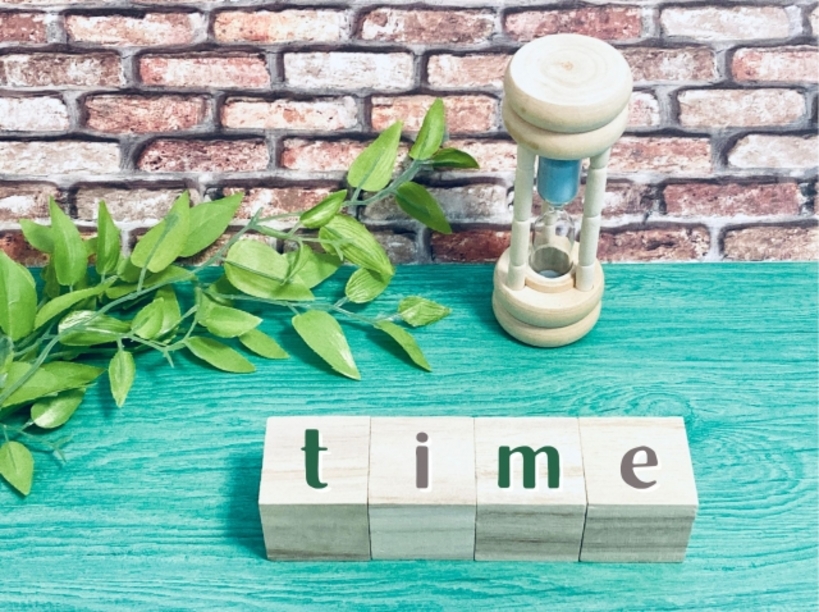 timeと書かれたブロックと砂時計と造花の葉