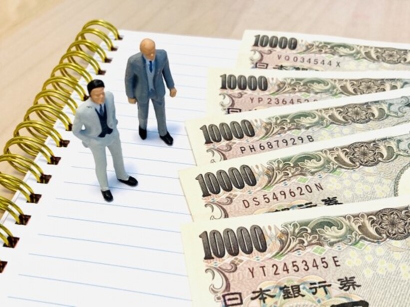 1万円札を眺める2人のビジネスマン